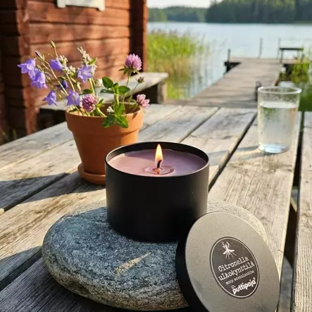 Citronella-ulkotuli laiturilla tai terassipöydällä; musta metallipurkki ja kynttilän kansi luonnonläheisessä kesäympäristössä. - Ulkotulet - 175302025-30AC - 2